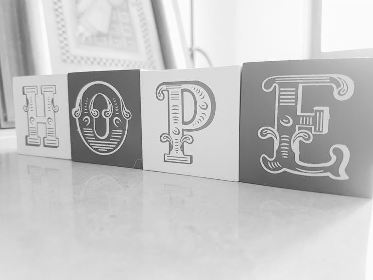 Elegant monochrome blocks spell out 'HOPE' on a reflective surface.